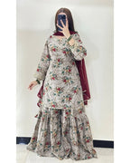 A woman takes a mirror selfie wearing a traditional three-piece salwar kameez set. The set features a light beige kurta and flared pants with a red, green, and blue floral pattern, paired with a deep maroon dupatta.