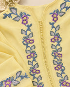 Close-up of a pale yellow embroidered garment with purple flowers and blue-green leaves running vertically along the front, featuring a decorative bead-like center zipper detail.