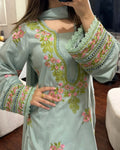 Light blue embroidered dress with floral patterns worn by a person indoors.