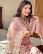 Woman in a pink traditional outfit with gold accents, sitting indoors.